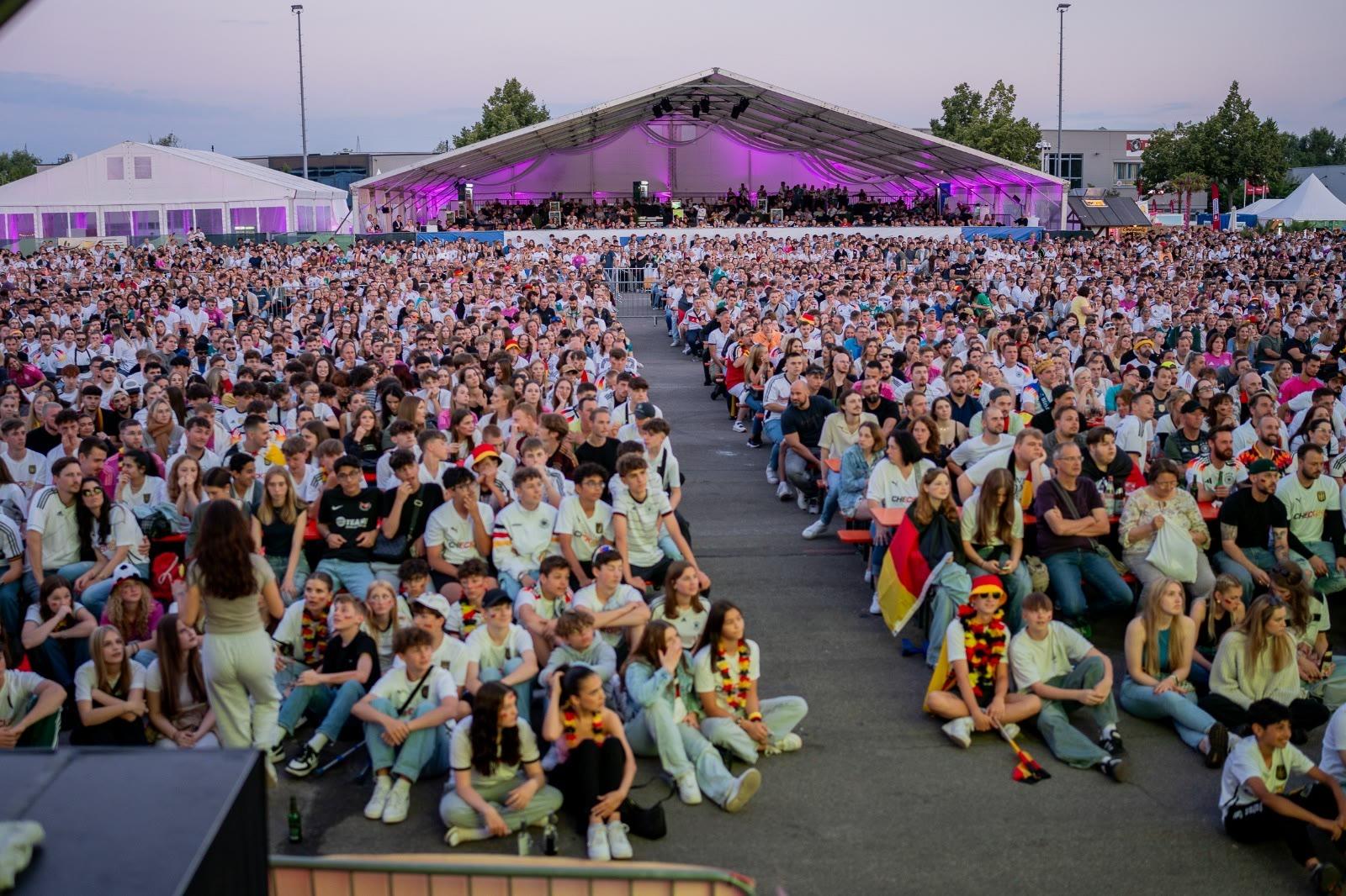 Tausende Zuschauer vor der Großleinwand in der Arena bei Dämmerung